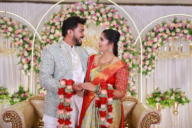 Akhil and Rachana together beneath the flower arch
